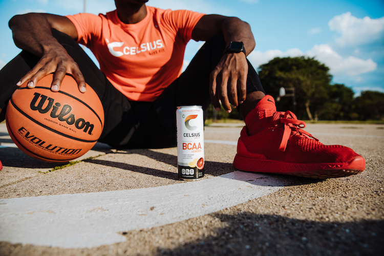 image of a man sitting next to a basketball and a bcaa celsius can